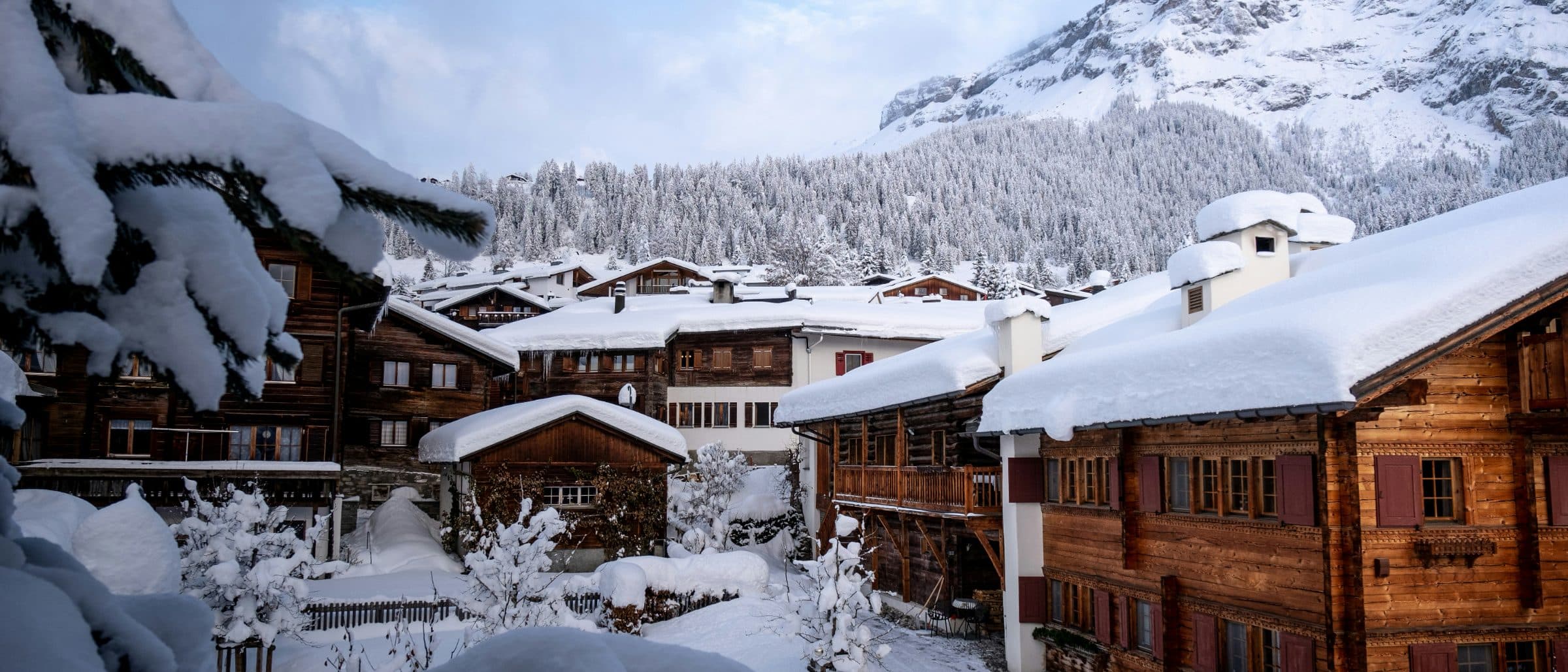 Village de chalets en bois enneigés au pied des montagnes
