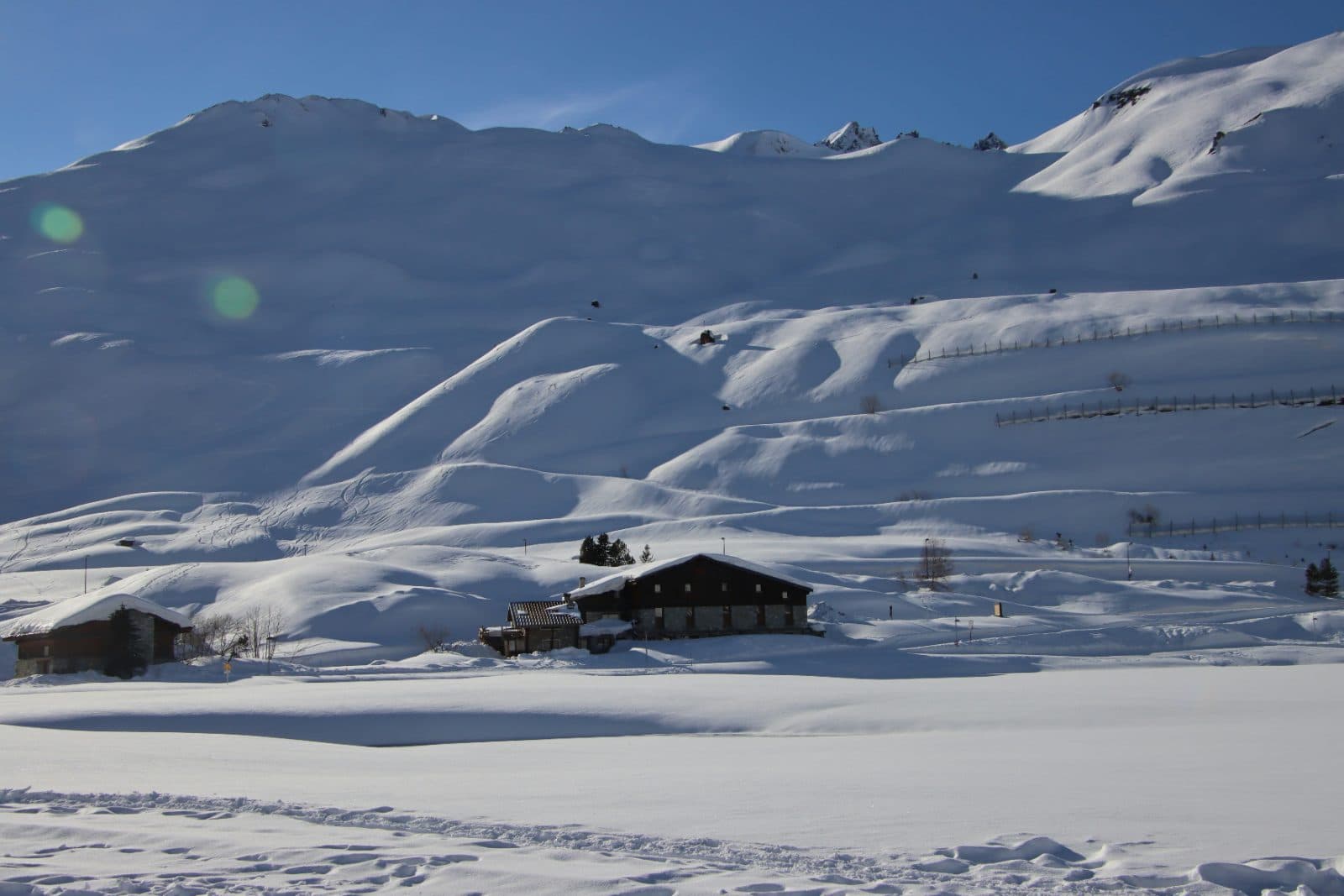 Chalet d'alpage au pied de pentes enneigées, sous un ciel bleu