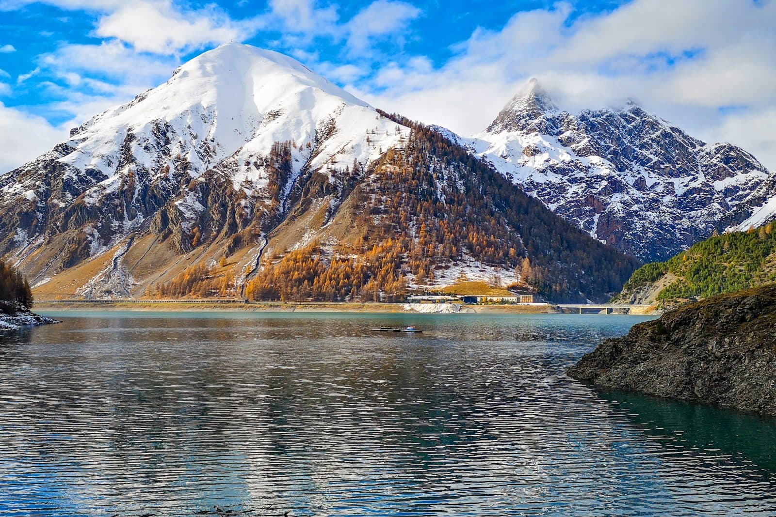 Sommets enneigés et mélèzes d'automne au-dessus d'un lac de montagne